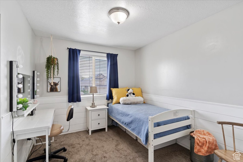 Bedroom featuring wainscoting, carpet flooring, and a textured ceiling