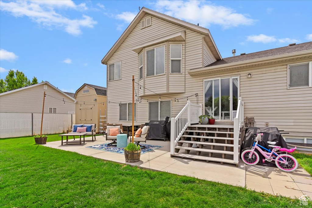 Back of property featuring fence, a lawn, an outdoor living space, and a patio area