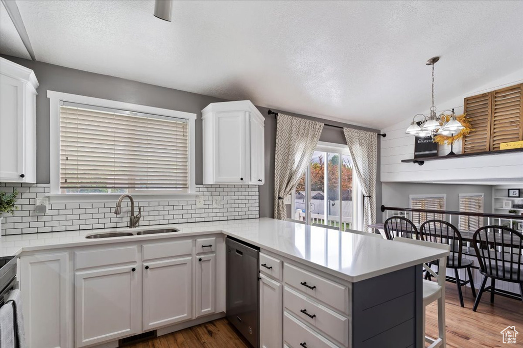 Kitchen featuring decorative backsplash, appliances with stainless steel finishes, a sink, white cabinets, and a peninsula