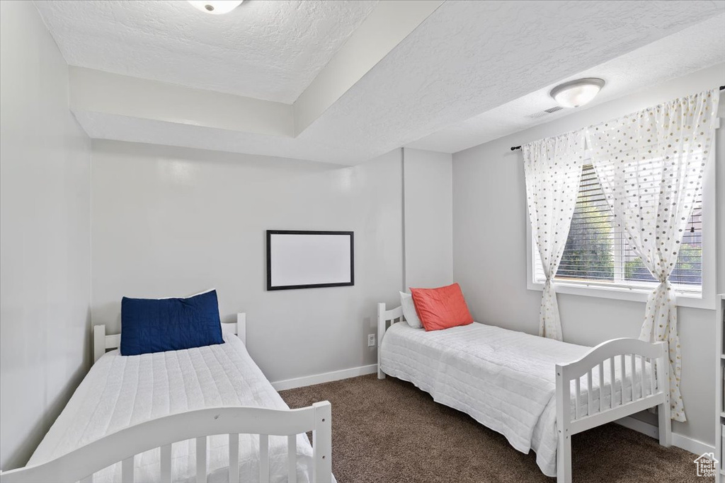 Bedroom featuring baseboards, carpet flooring, and a textured ceiling