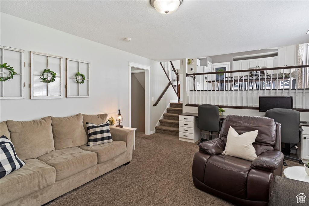 Living room with carpet floors, a textured ceiling, and stairs