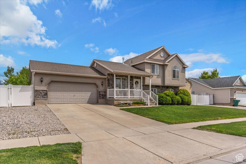 Split level home featuring a gate, stucco siding, and stone siding