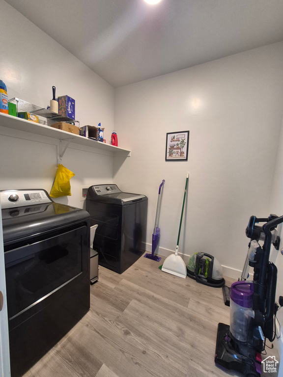 Washroom with baseboards, laundry area, light wood-type flooring, and washer and dryer