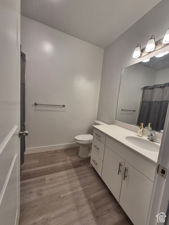 Bathroom featuring vanity, a textured ceiling, wood finished floors, and toilet