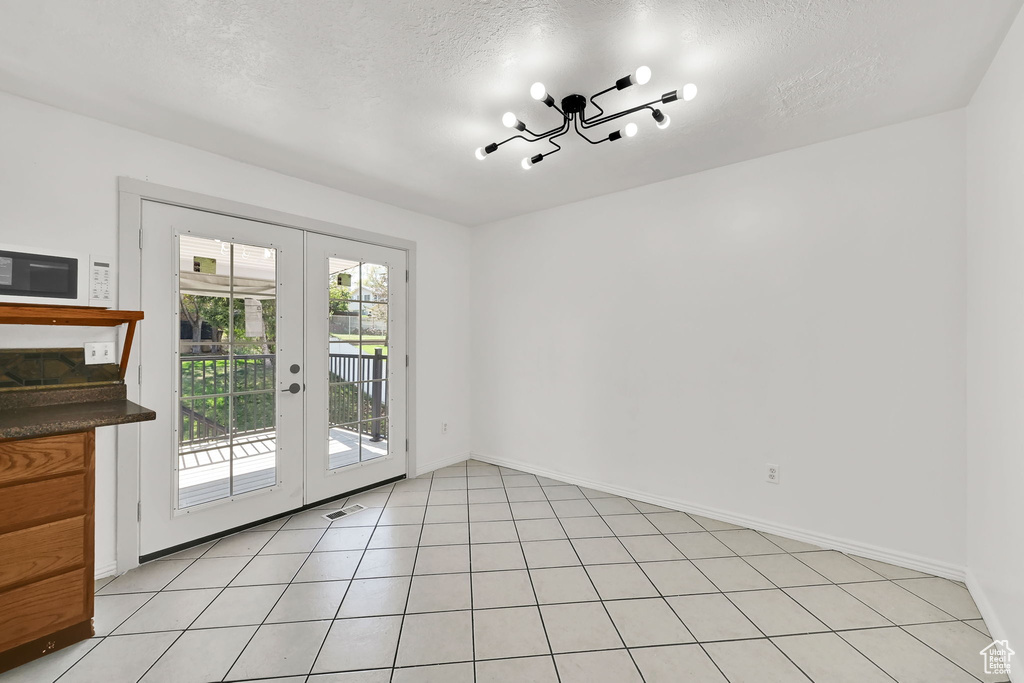 Interior space with french doors, a textured ceiling, baseboards, and visible vents