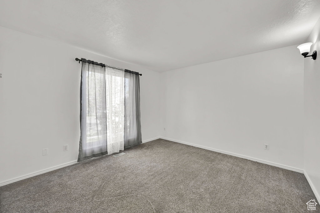 Unfurnished room featuring carpet floors, baseboards, and visible vents