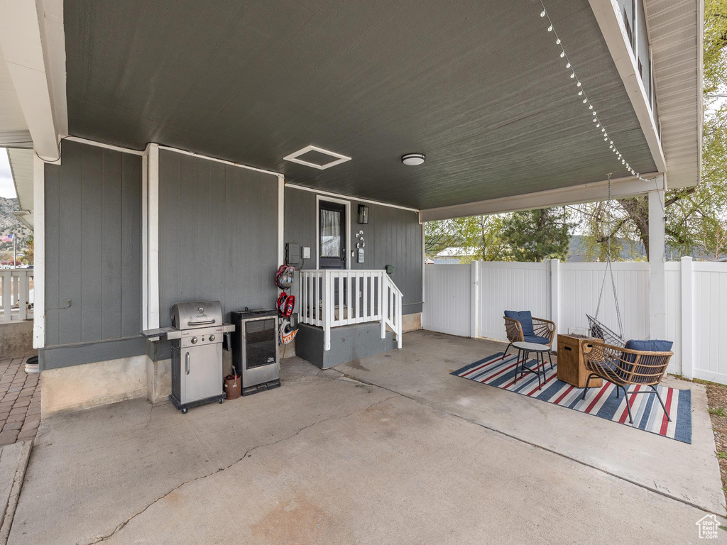 View of patio with fence and a grill
