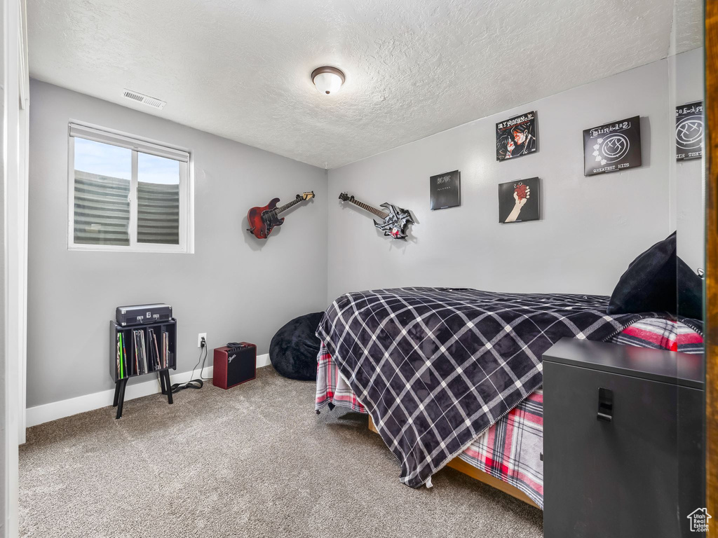 Bedroom with carpet flooring, a textured ceiling, visible vents, and baseboards
