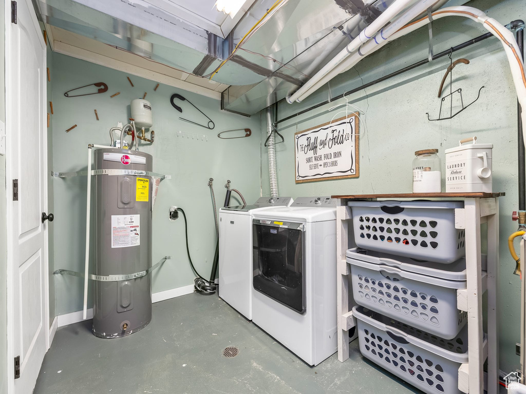 Clothes washing area featuring washer and dryer, baseboards, laundry area, and water heater