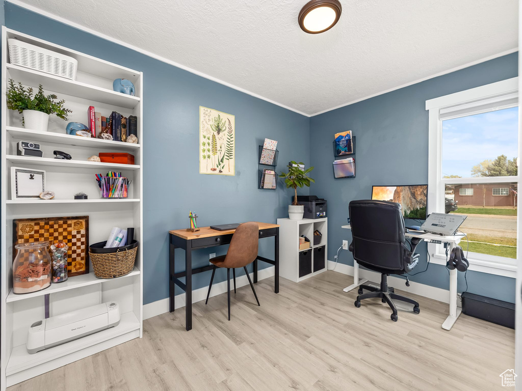 Office space featuring a textured ceiling, baseboards, ornamental molding, and wood finished floors