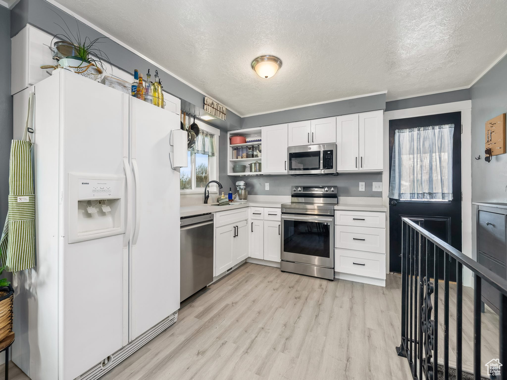 Kitchen featuring light wood-type flooring, a sink, white cabinetry, and stainless steel appliances