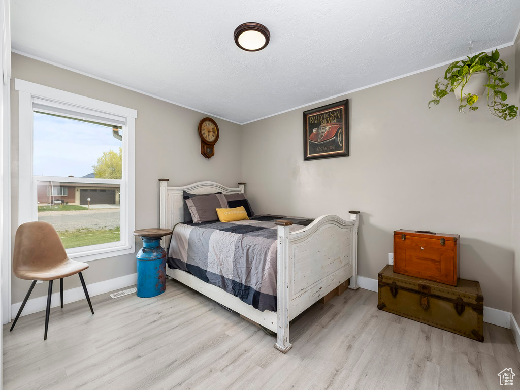 Bedroom featuring crown molding, baseboards, wood finished floors, and visible vents
