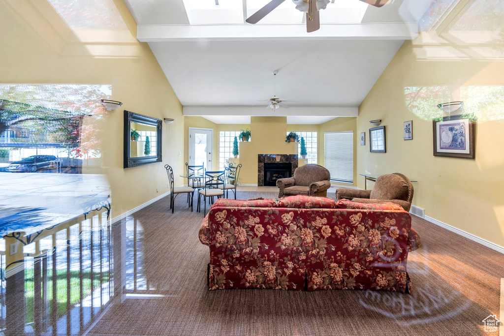 Living area with baseboards, ceiling fan, a fireplace, and high vaulted ceiling