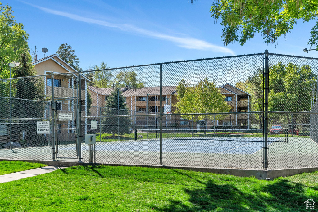 View of tennis court with a gate, fence, and a yard