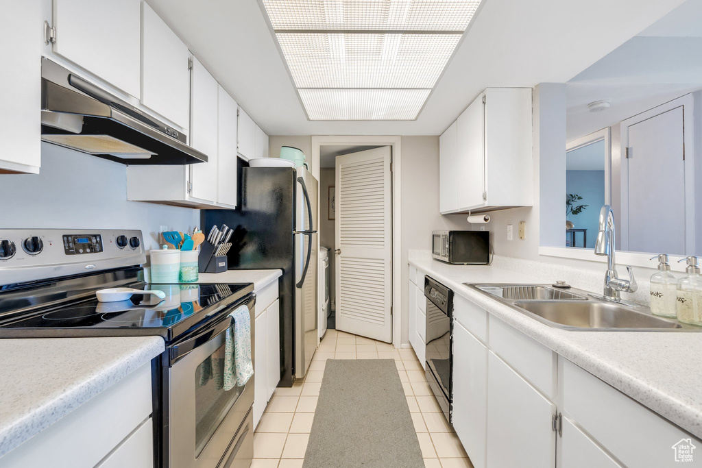 Kitchen featuring a sink, light tile patterned floors, white cabinets, under cabinet range hood, and stainless steel appliances