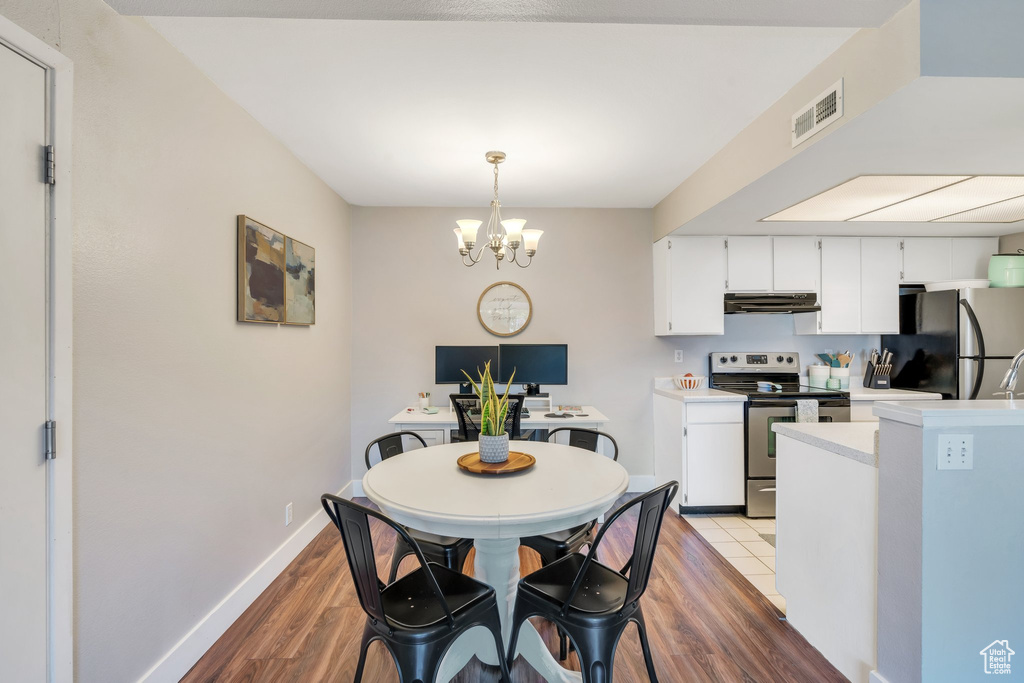 Dining space with visible vents, baseboards, wood finished floors, and an inviting chandelier