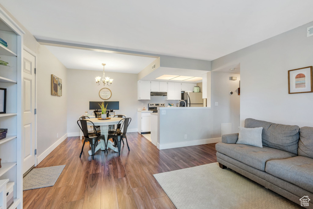 Living room with baseboards, wood finished floors, a notable chandelier, and visible vents