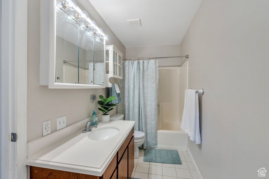 Bathroom with vanity, toilet, tile patterned floors, baseboards, and shower / tub combo