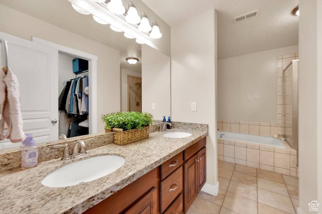 Bathroom featuring a relaxing tiled tub, a sink, tile patterned floors, and visible vents