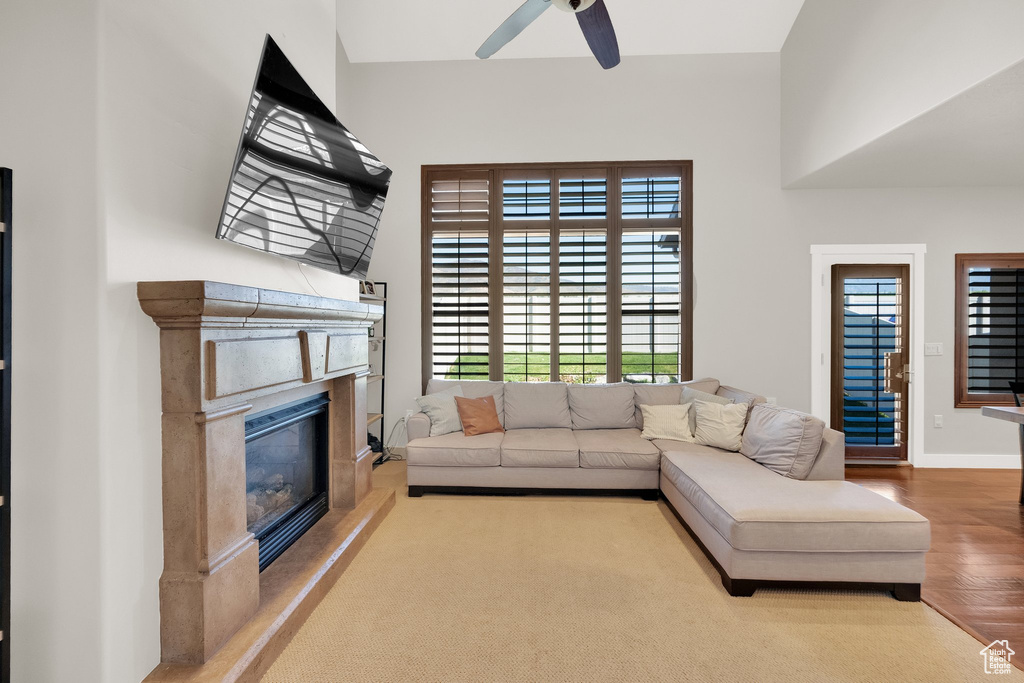 Living area with plenty of natural light, a fireplace, ceiling fan, and wood finished floors
