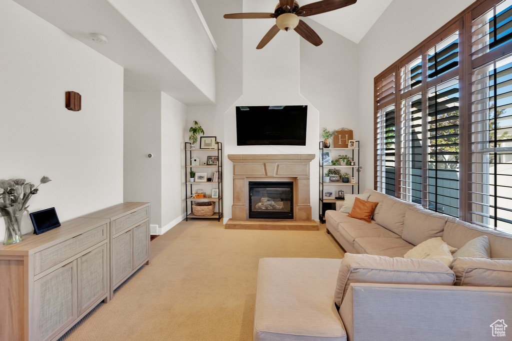 Living room with plenty of natural light, a glass covered fireplace, ceiling fan, and light colored carpet