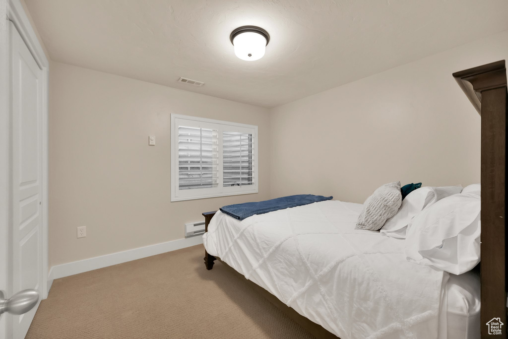 Bedroom with visible vents, a baseboard radiator, baseboards, and light carpet