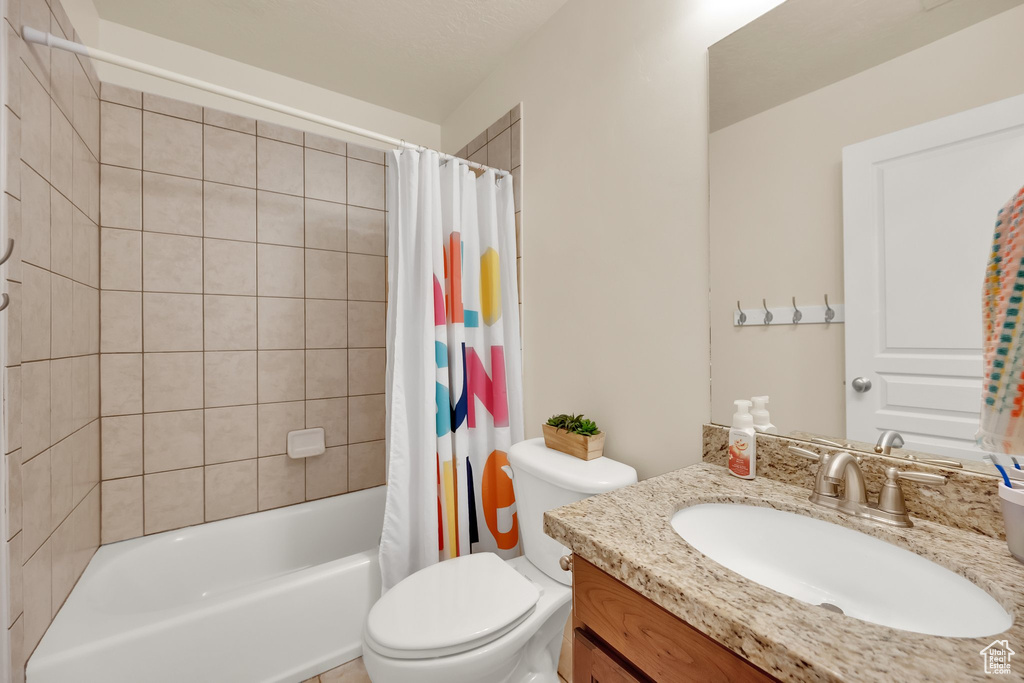Full bathroom with toilet, shower / bathtub combination with curtain, and vanity