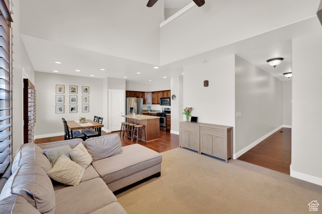 Living room featuring ceiling fan, light colored carpet, light wood-style floors, recessed lighting, and baseboards