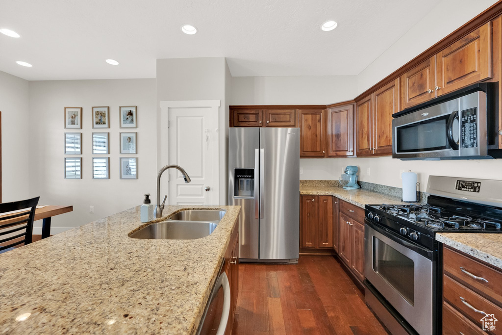 Kitchen featuring light stone countertops, a sink, stainless steel appliances, recessed lighting, and dark wood-style floors