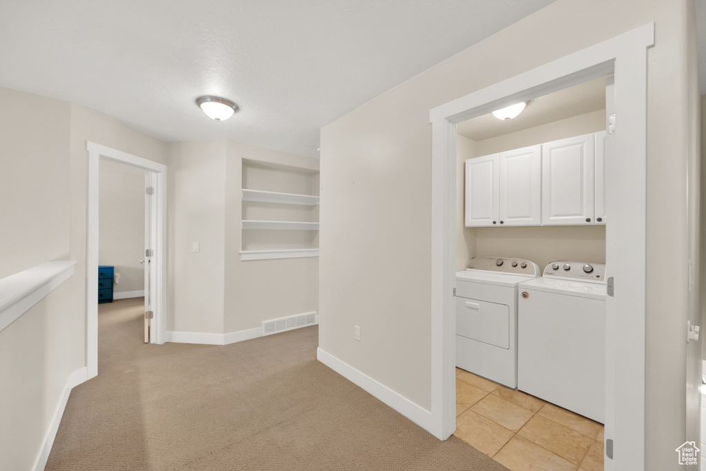 Laundry area featuring cabinet space, separate washer and dryer, built in shelves, baseboards, and visible vents
