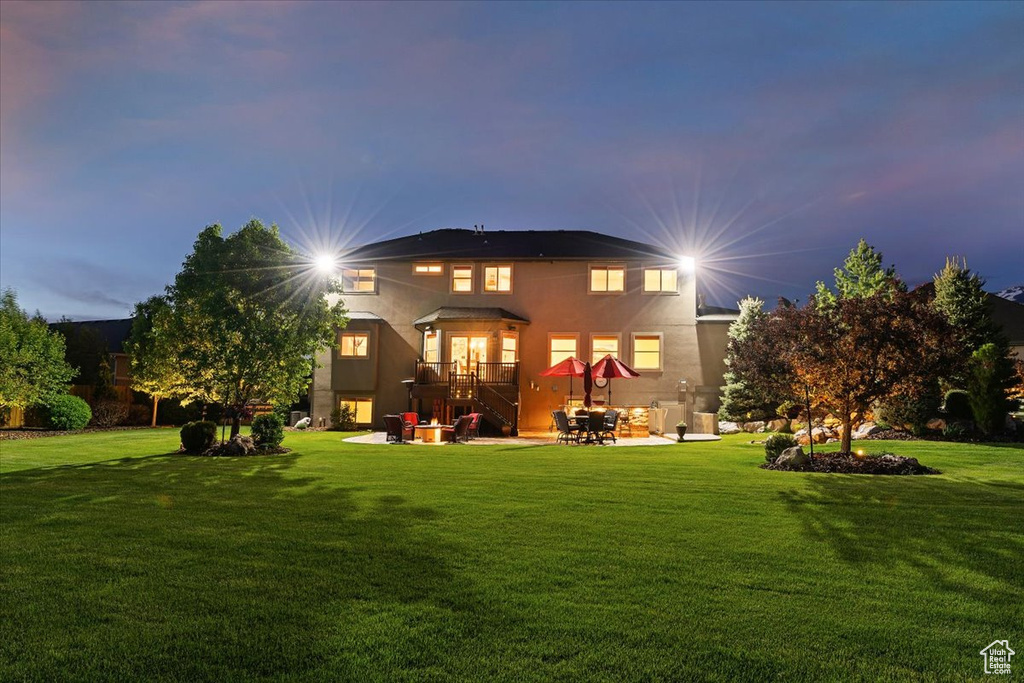 Rear view of house with a patio area, a yard, and stucco siding