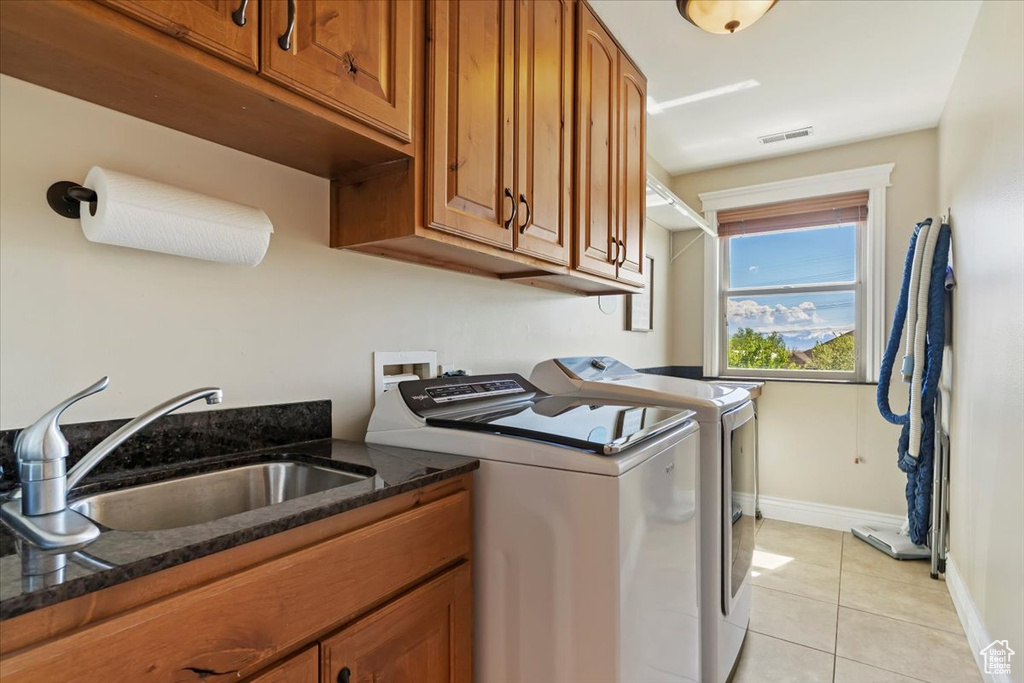 Washroom with visible vents, washing machine and clothes dryer, a sink, cabinet space, and light tile patterned floors