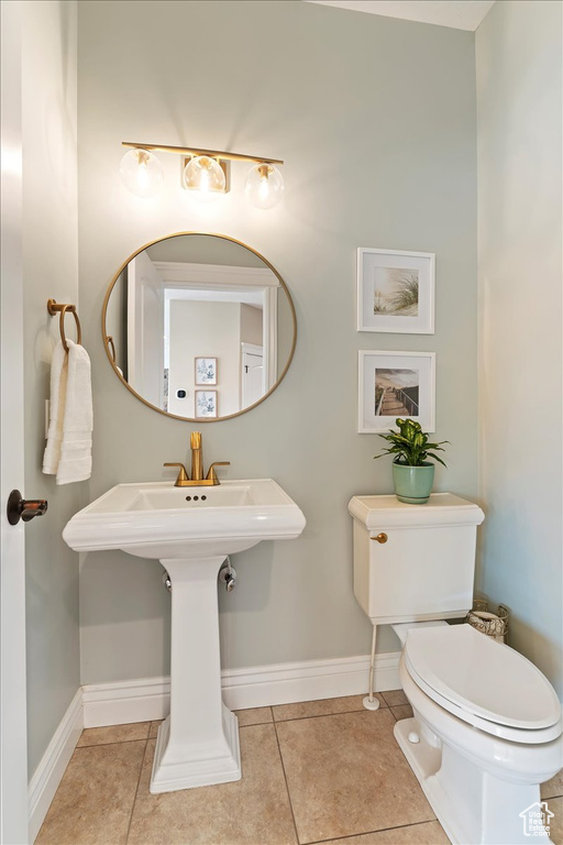 Half bath featuring baseboards, tile patterned flooring, and toilet