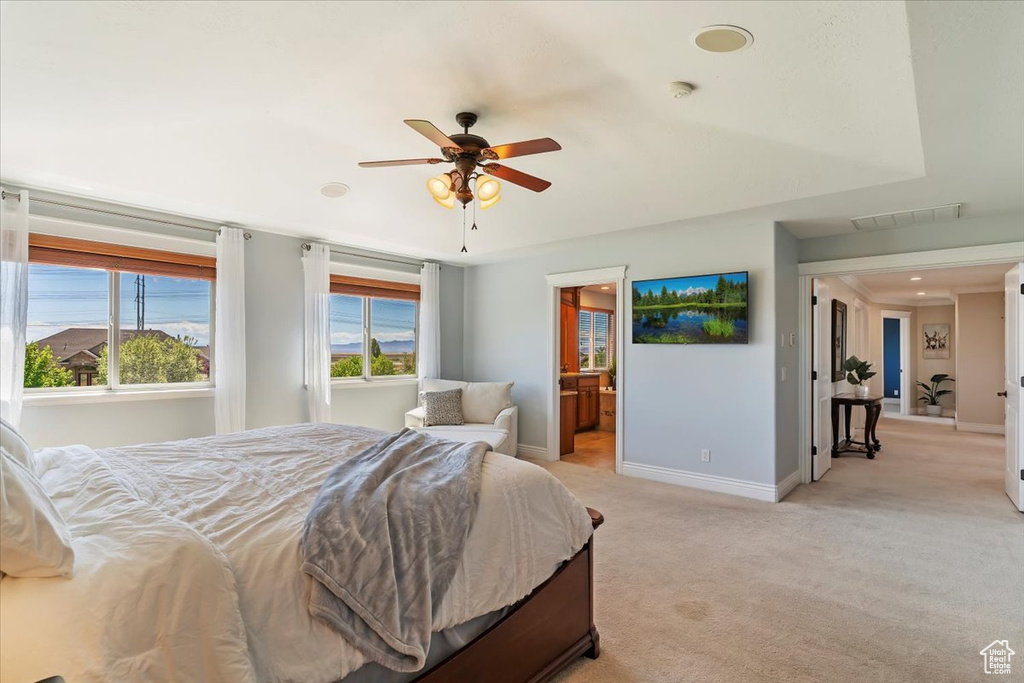 Bedroom with baseboards, visible vents, ensuite bath, and light colored carpet