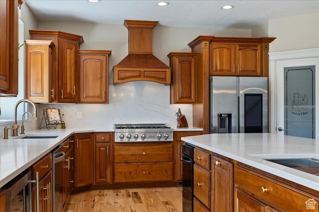 Kitchen with wine cooler, premium range hood, light countertops, a sink, and stainless steel appliances