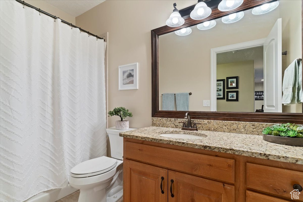 Bathroom featuring vanity, curtained shower, and toilet