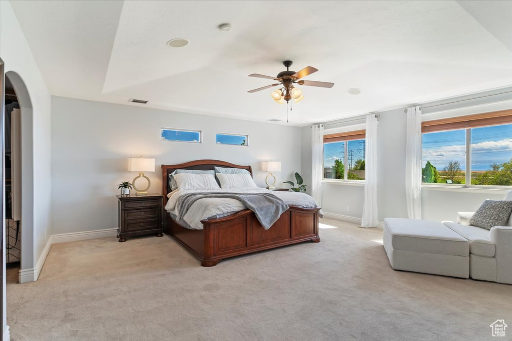 Bedroom featuring arched walkways, light colored carpet, visible vents, and baseboards