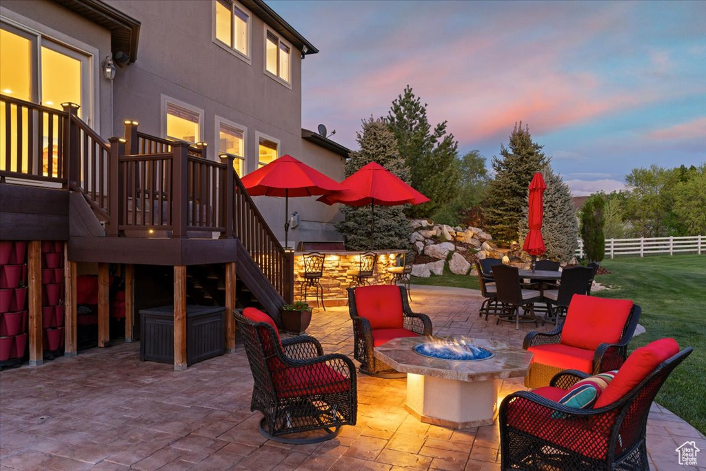 Patio terrace at dusk featuring an outdoor living space with a fire pit, fence, and stairway