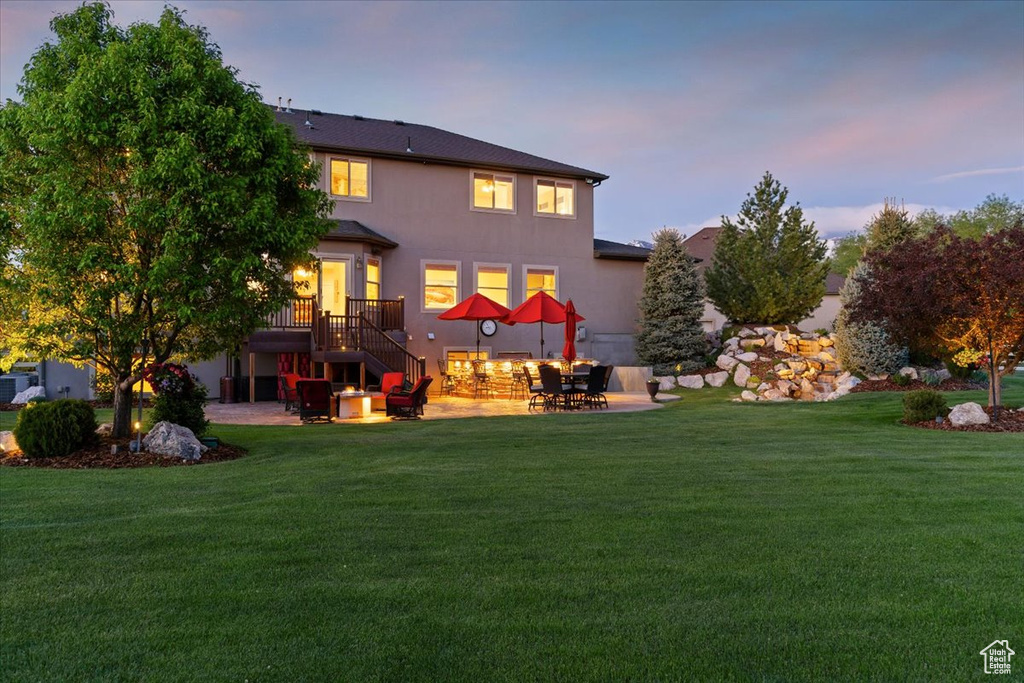 Back of property with a patio area, a lawn, stairs, and stucco siding