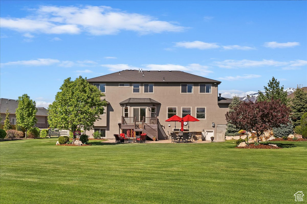 Rear view of property with a patio, stucco siding, and a yard