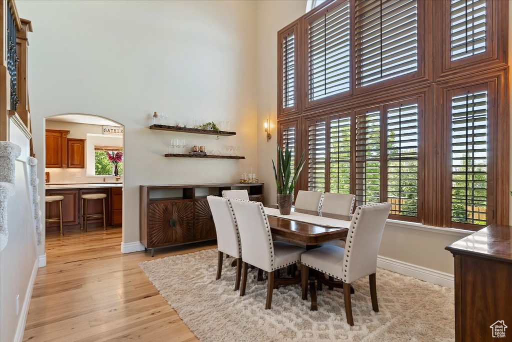Dining area featuring a high ceiling, plenty of natural light, baseboards, and light wood-type flooring