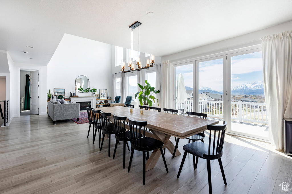 Dining area with a glass covered fireplace, a mountain view, light wood finished floors, and a chandelier