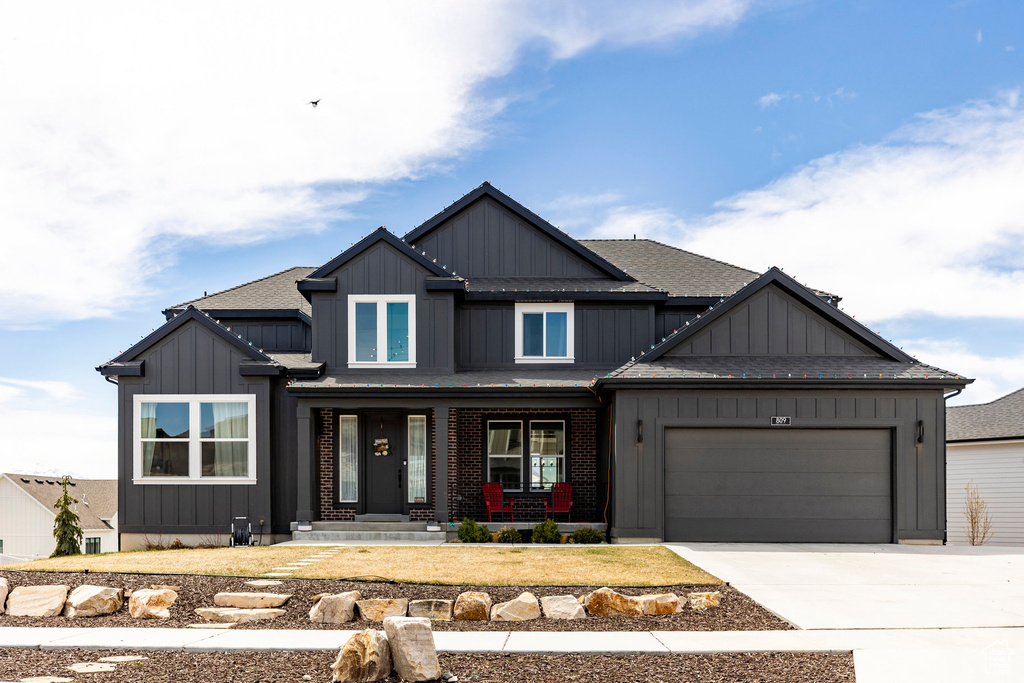 Craftsman-style home featuring a garage, board and batten siding, driveway, and covered porch