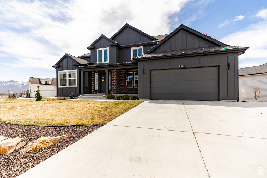 Craftsman-style house with board and batten siding, a front yard, a garage, a mountain view, and concrete driveway
