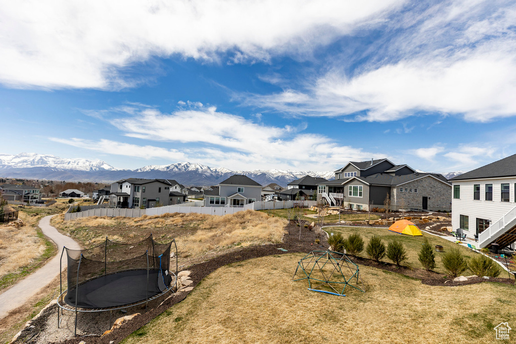 View of yard with a residential view, a trampoline, and a mountain view