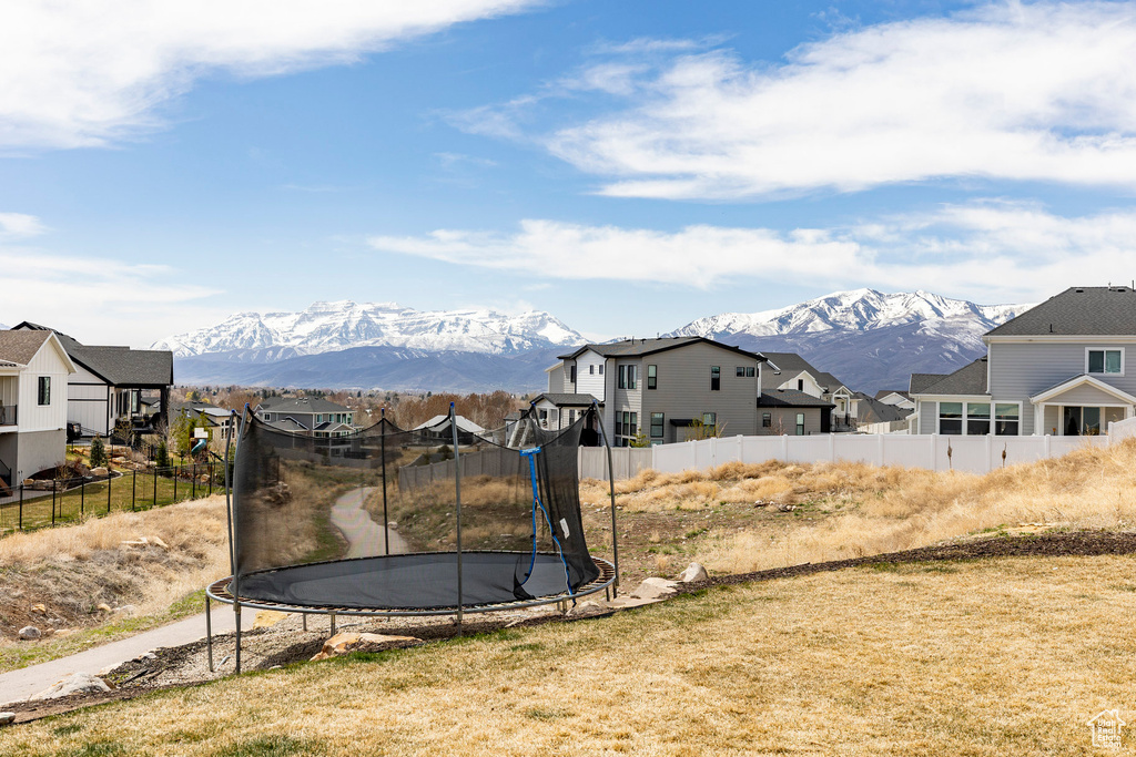 View of yard featuring a trampoline, a mountain view, a residential view, and fence