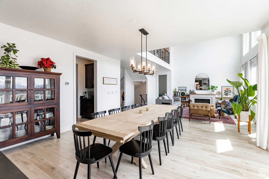 Dining room featuring a fireplace, light wood-style flooring, and a notable chandelier