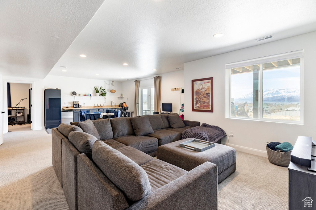 Living room featuring bar, visible vents, baseboards, light carpet, and recessed lighting