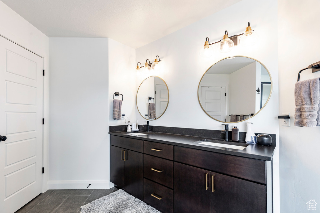 Full bath with double vanity, baseboards, a sink, and tile patterned flooring