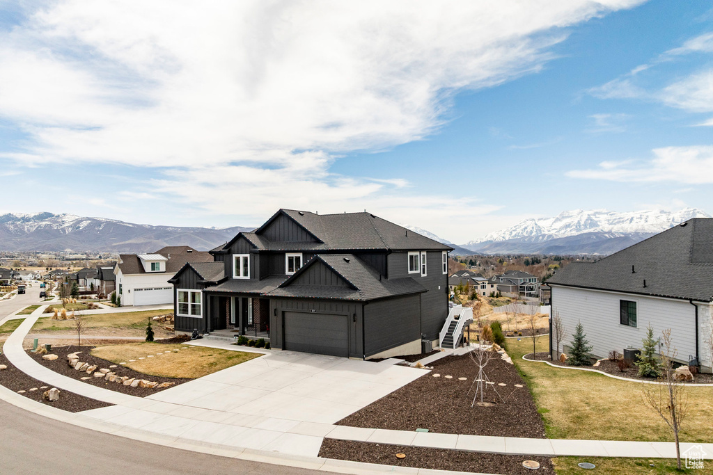 View of front of house with board and batten siding, a residential view, a mountain view, concrete driveway, and an attached garage